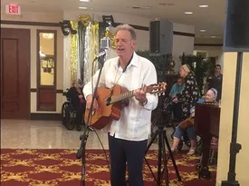 Alan Cohen playing guitar for a senior community audience