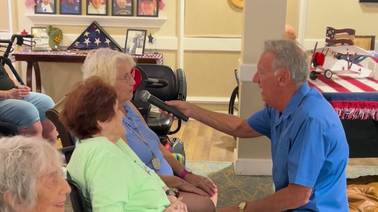 Alan kneeling beside residents and sharing the microphone