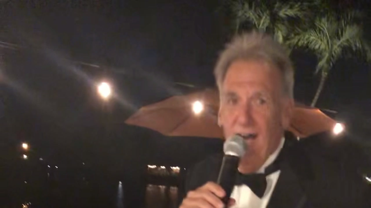 Alan singing My Eyes Adored You among guests at a formal celebration
